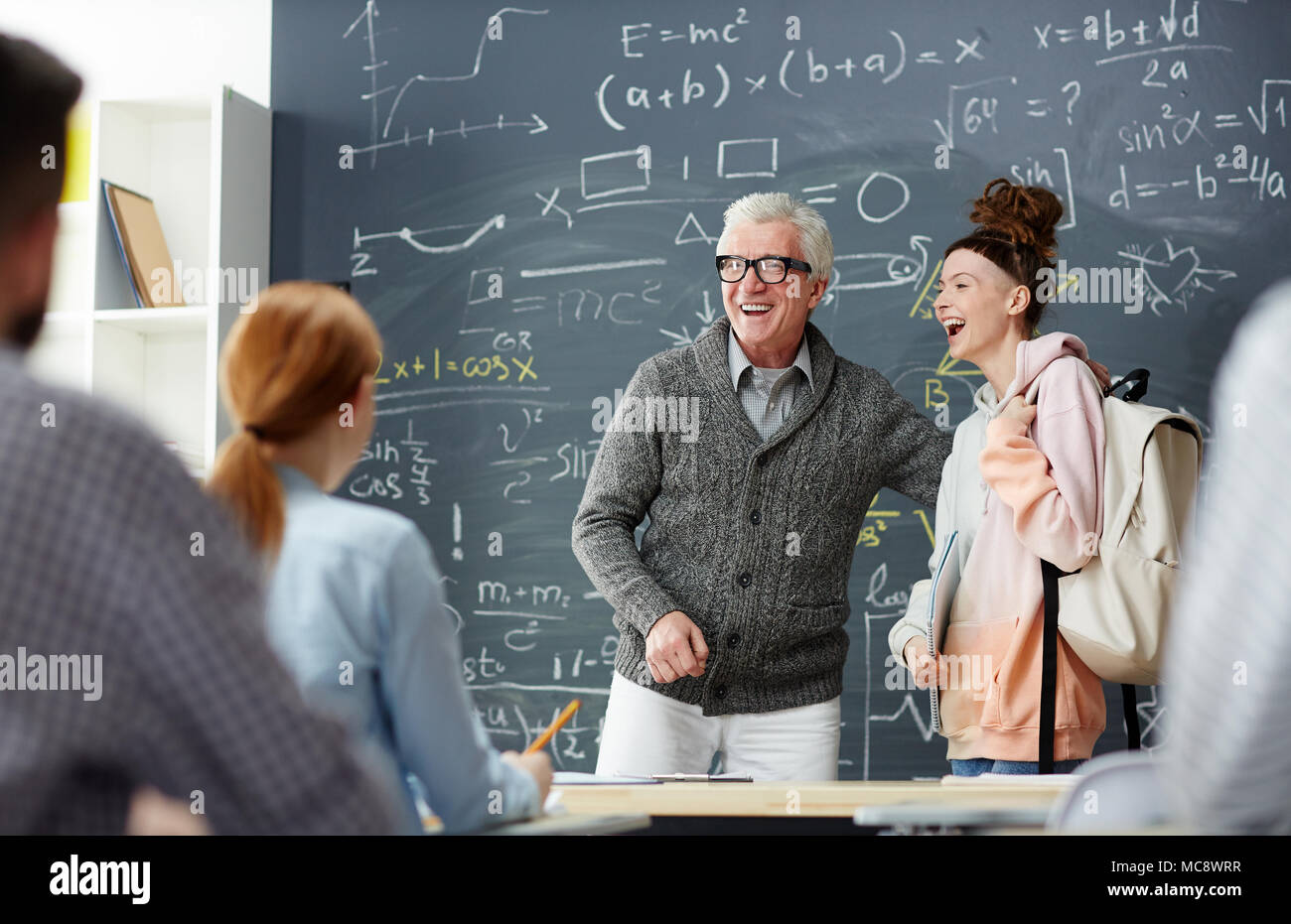 Lachen Lehrer und einem Schüler von blackboard stand vor der groupmates Stockfoto