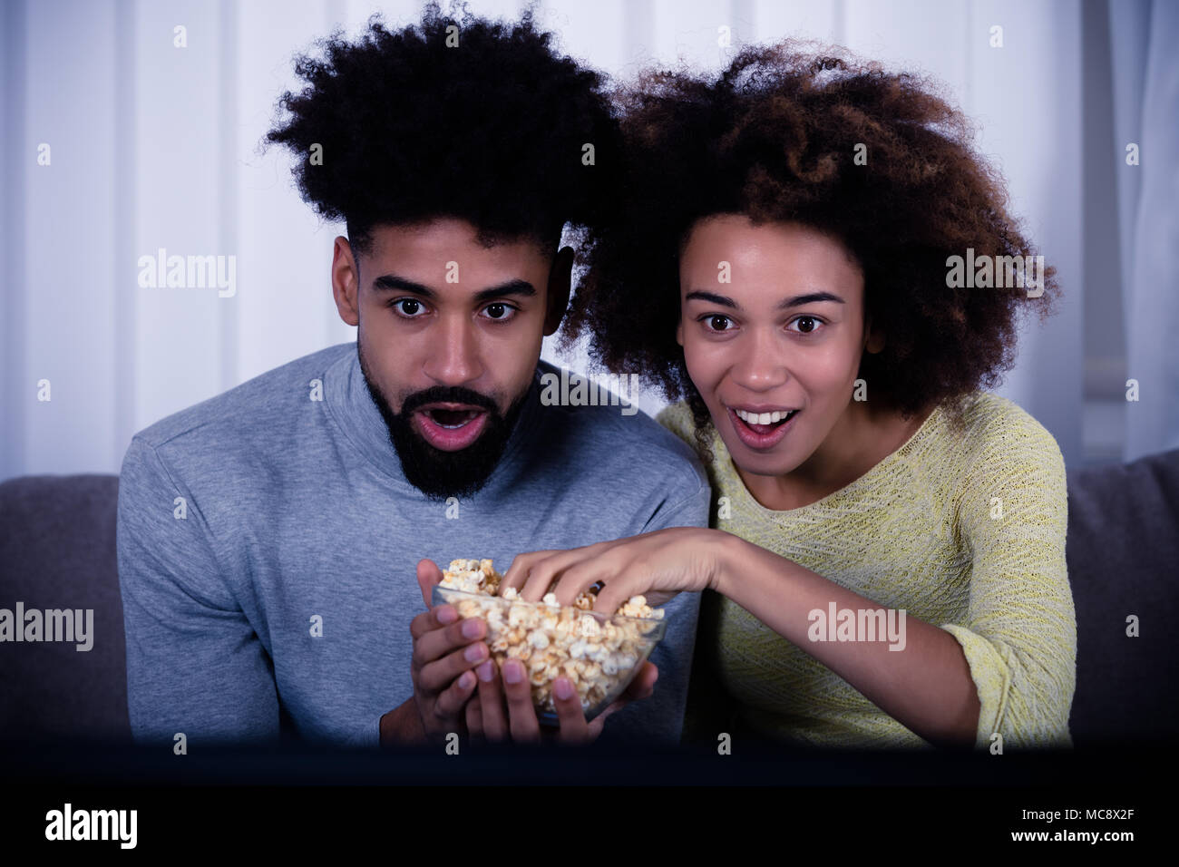 Schockiert Paar Popcorn zu essen, während Sie Film Stockfoto