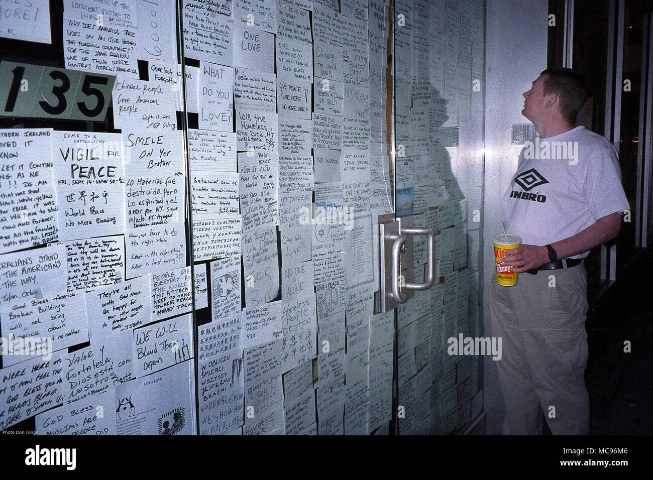 Darren Lowe ein Tourist aus dem Vereinigten Königreich wird dargestellt, an einigen der Tribute und Kommentare von New Yorkern auf dem Glas Türen eines Gebäudes links am Tag nach dem Terroranschlag auf das World Trade Center in New York City auf 9/11 Foto DON TONGE Fotograf, Stockfoto