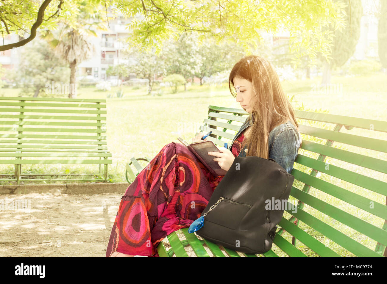 Eine schöne junge Frau auf einer Parkbank sitzt der Feder Stockfoto