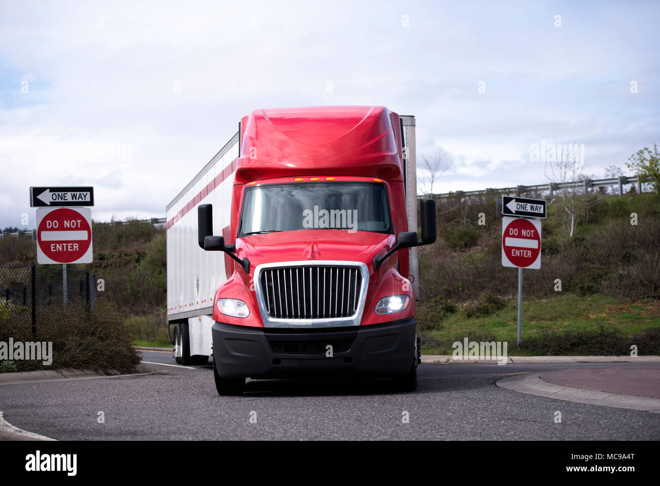 Big Rig American Industrial Semi Truck mit trockenen van Auflieger drehen von der Autobahn auf den kreisförmigen Kreuzung der Ausfahrt unter Brücke mit Stockfoto