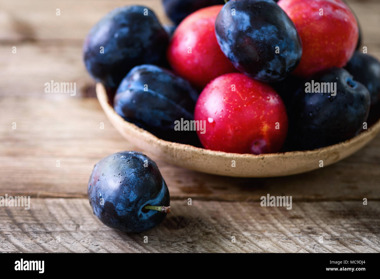 Blau und pink Bio Pflaumen auf dunklem Hintergrund. Copyspace. Stockfoto