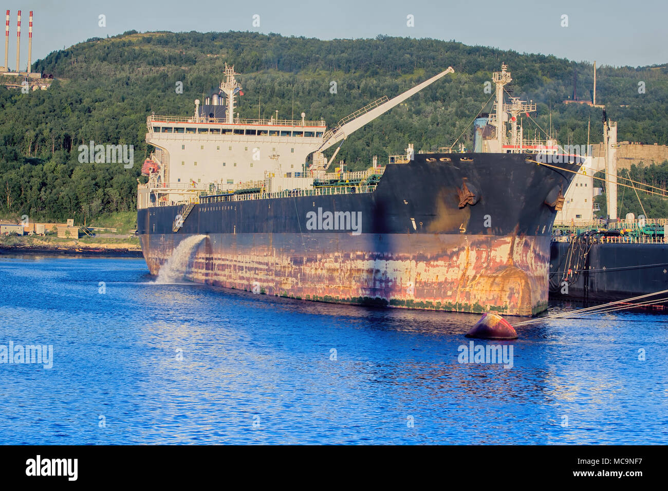 Cargo Schiff am Pier wenig North Port. Ballastwasser (Eigengewicht) ins Meer entlassen wird, bevor sie den Laden (Entwurf, das Schiff unten). Meeresverschmutzung und Stockfoto