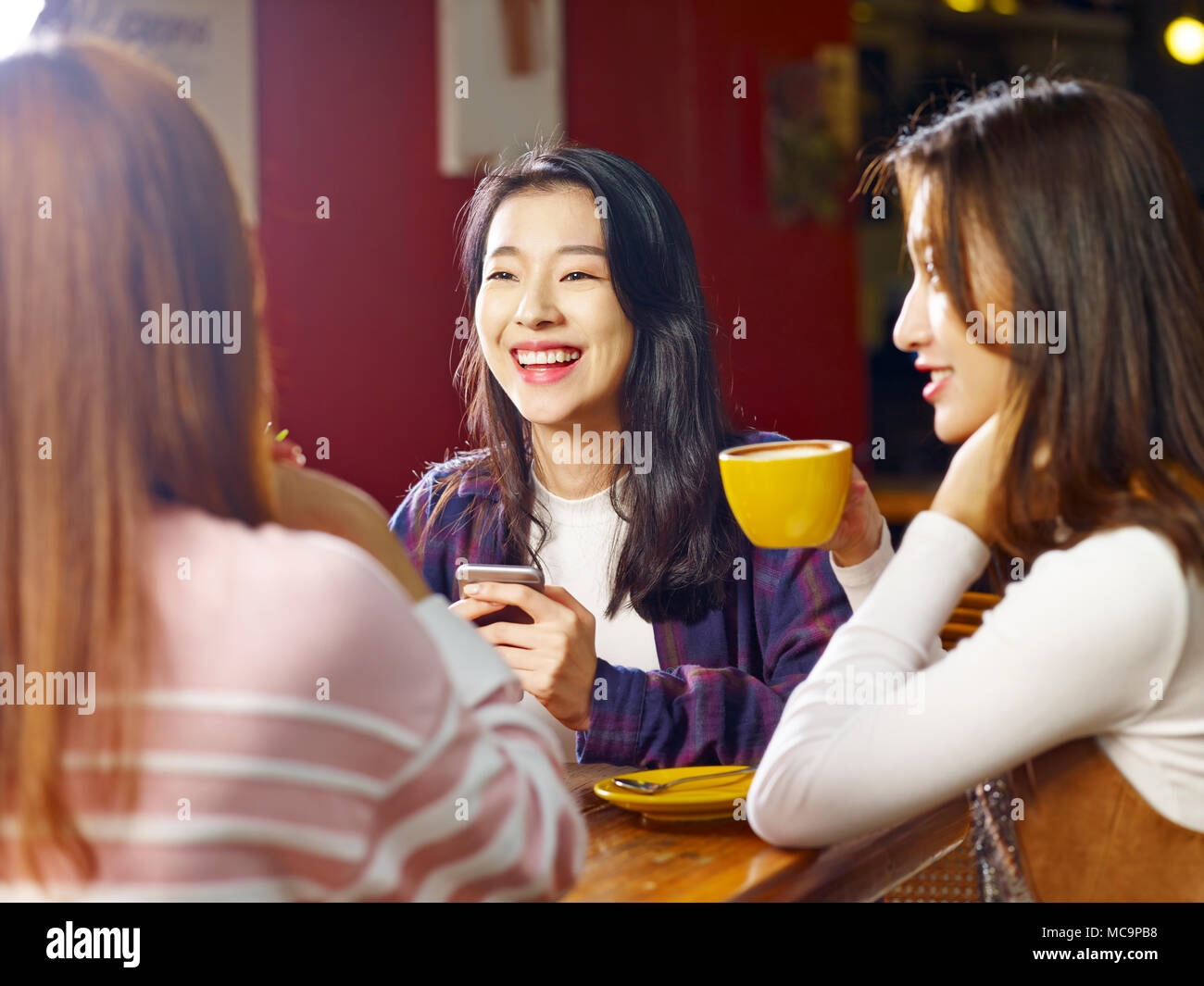 Drei glückliche wunderschöne junge asiatische Frauen am Tisch sitzen, plaudern, im Café oder Tee Haus. Stockfoto