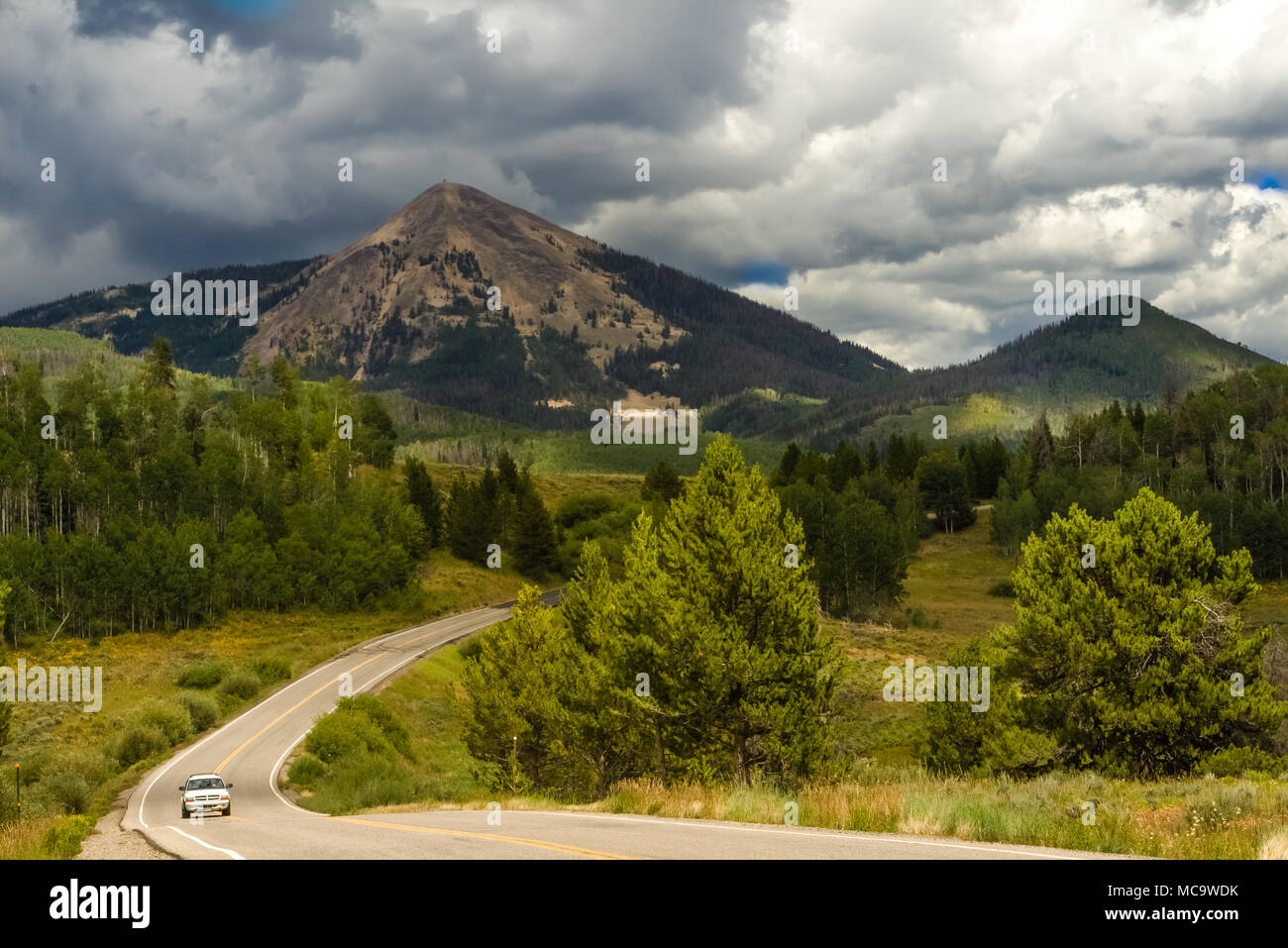 Blick auf eine Straße zwischen Gipfeln in Colorado, USA; stürmische Wolken über den Gipfeln; ein Auto fahren Stockfoto