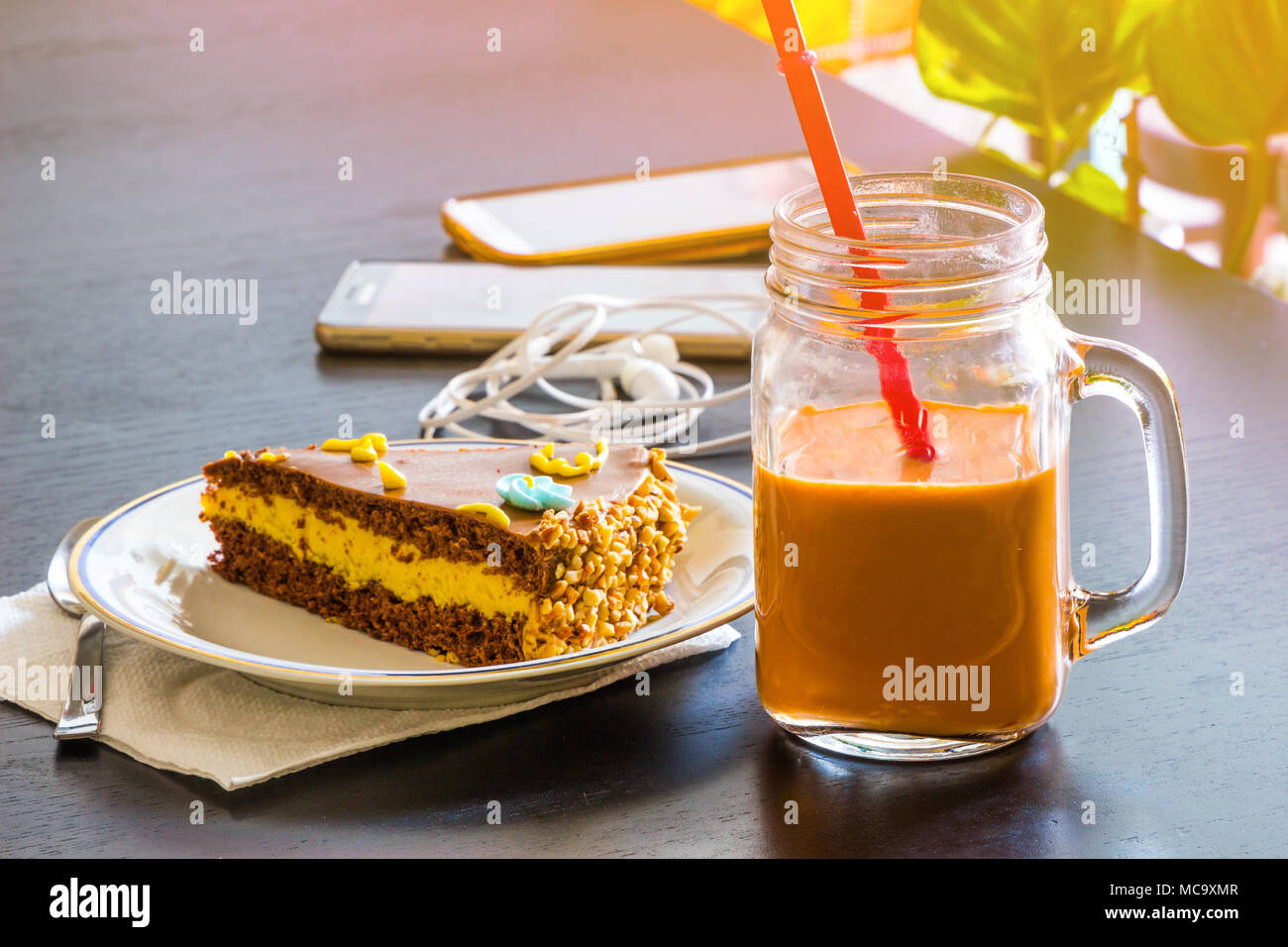 Köstliche Schokolade Kuchen und Smartphone mit Eistee Glas- oder Orangensaft im Coffee Shop in der Tabelle verschwommenen Hintergrund. Stockfoto
