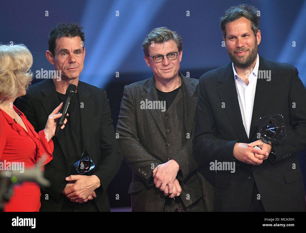 13 April 2018, Deutschland, Marl: Die Regisseure Tom Tykwer (L), Henk Handloegten (C) und Achim von Borries (R) die Auszeichnung in der Kategorie "Fiktion empfangen' (lit. Fiction) für die Serie 'Babylon Berlin' während der 54 Grimme Preis. Foto: Henning Kaiser/dpa Stockfoto