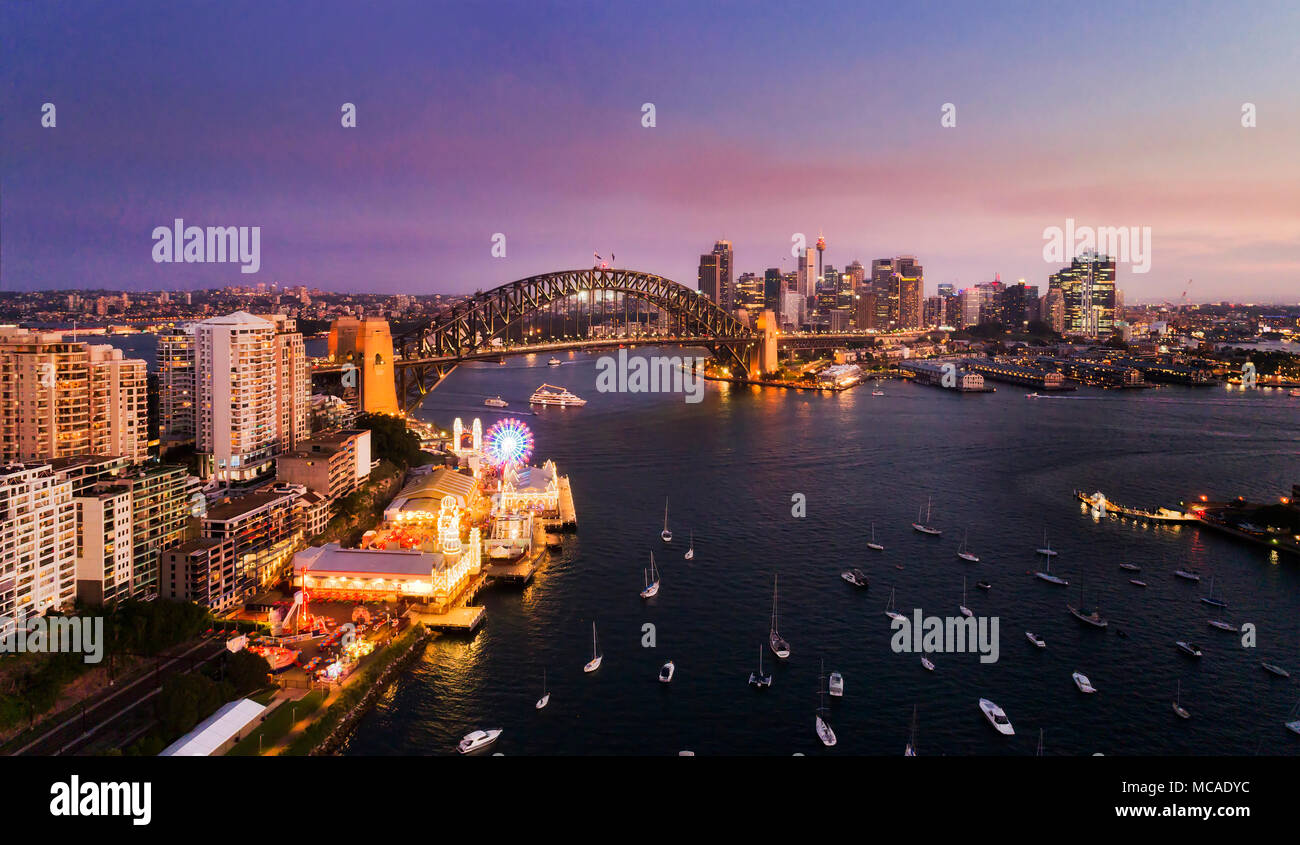 Dunkle Sonnenuntergang über Sydney Sehenswürdigkeiten rund um Sydney Harbour auf beiden Seiten der Sydney Harbour Bridge im Luftbild über die Wasser des Lavendels Bucht mit Schwimmstellung Stockfoto