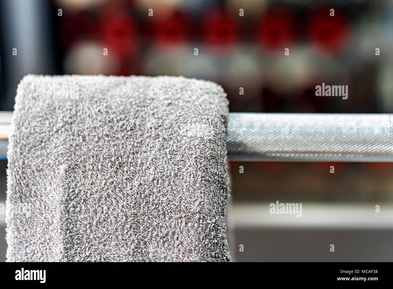 Grau Handtuch hängt an Barbell in der Turnhalle Stockfoto