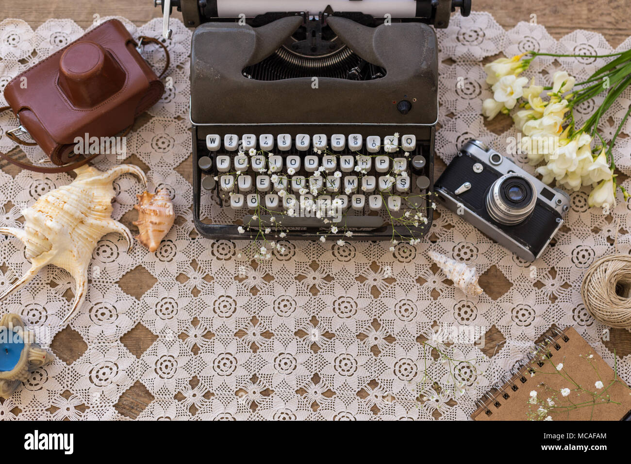 Frühling und Sommer flatlay für Unternehmen, Autoren, Blogger und Webseiten mit retro Schreibmaschine, vintage Film Kamera, Blumen, Muscheln und Blumen. Stockfoto