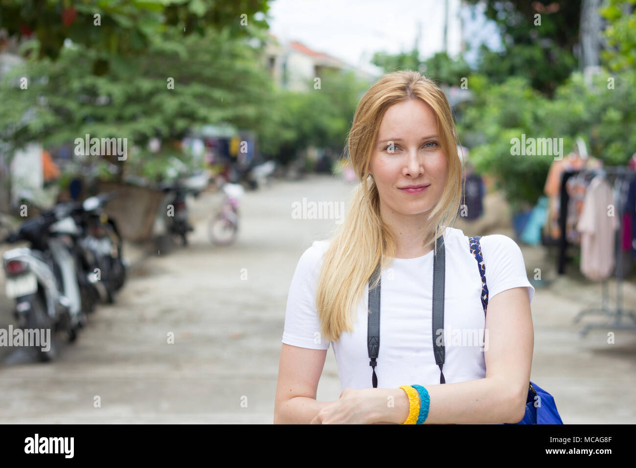 Fröhliche junge Frau touristische lächelnd und mit Blick auf die Kamera auf der Straße Stockfoto