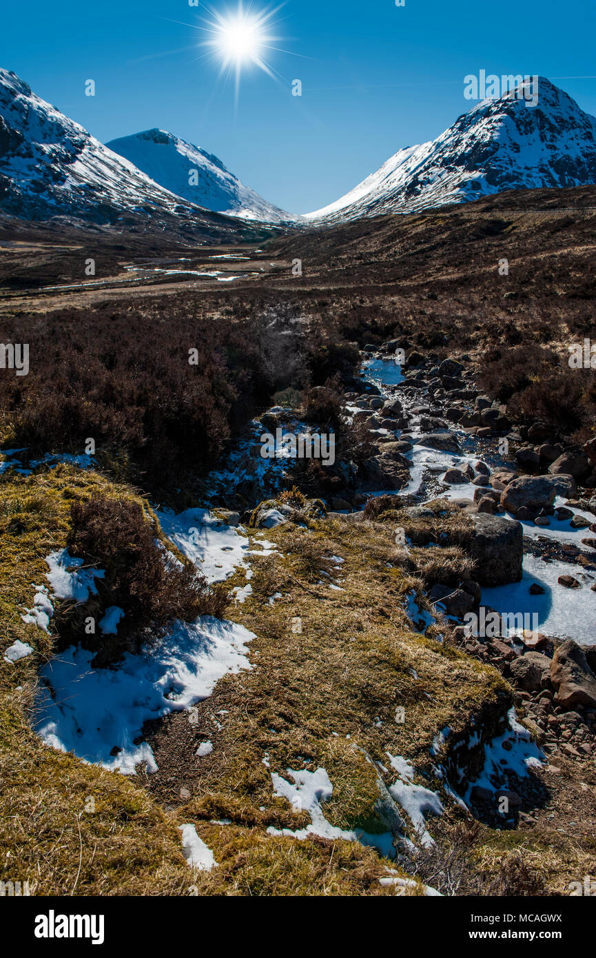 Die atemberaubende Aussicht auf die schottischen Highlands - eine helle Sonne strahlt auf die Berge von Glencoe Stockfoto