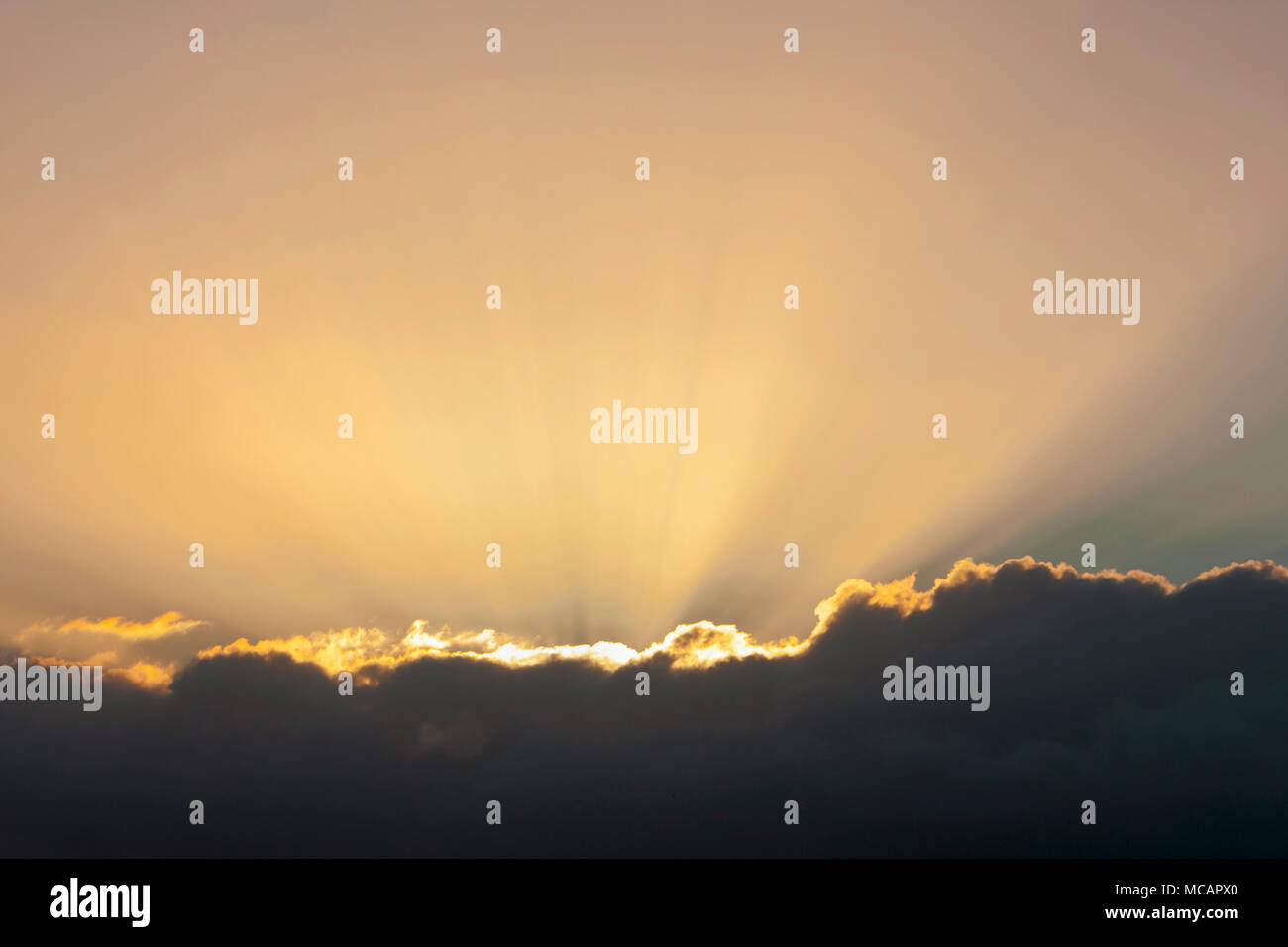 Golden Sun Balken aus hinter einer dunklen Wolken bei Sonnenuntergang Stockfoto