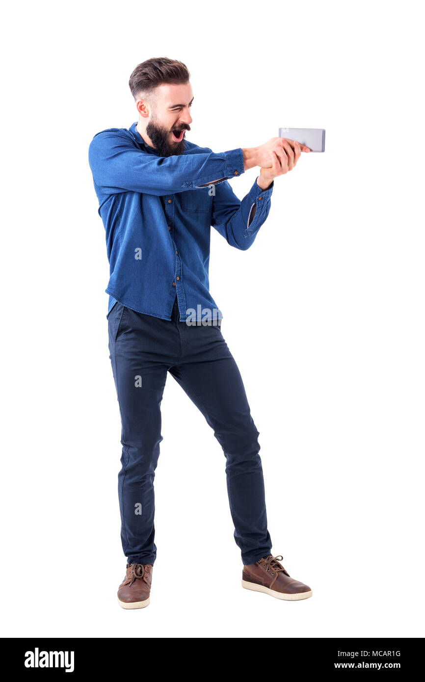 Verspielte business Mann mit Handy als Pistole, die darauf abzielen Action Film Hero. Voller Körper auf weißem Hintergrund. Stockfoto