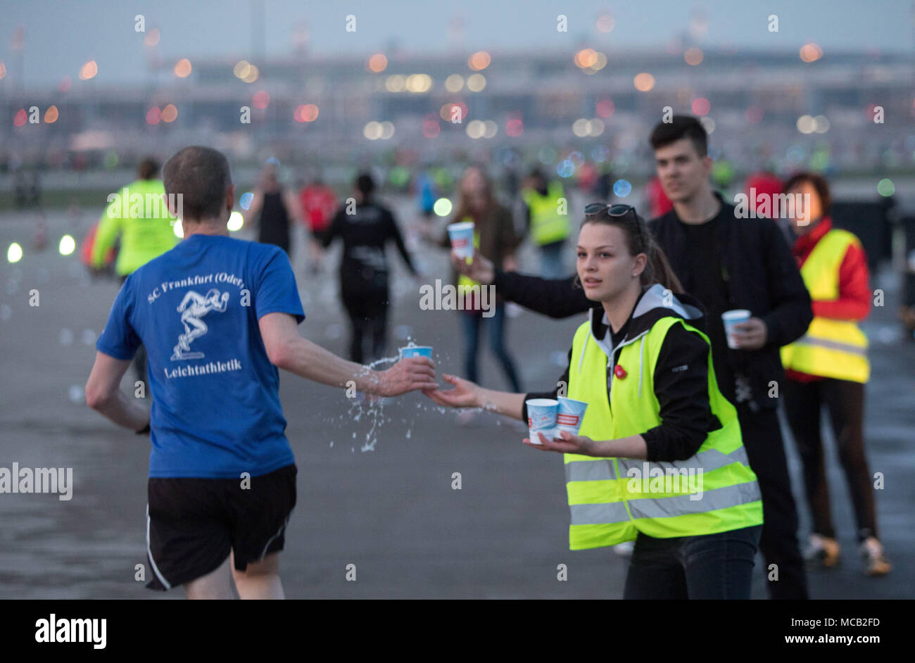 14 April 2018, Deutschland, Berlin-schönefeld: Helfer servieren Getränke an die Läufer auf der 12 Airport Night Run in die Zukunft Berlin Brandenburg Capital Airport. Foto: Jörg Carstensen/dpa Stockfoto