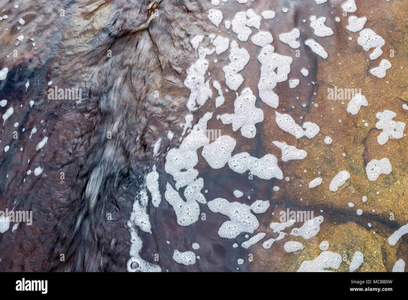 Schnell fließenden Kanal von Wasser in einem Datenstrom mit Schaum auf der Oberfläche und gritstone unter. Kinder Scout, Derbyshire, Peak District, England, Großbritannien Stockfoto