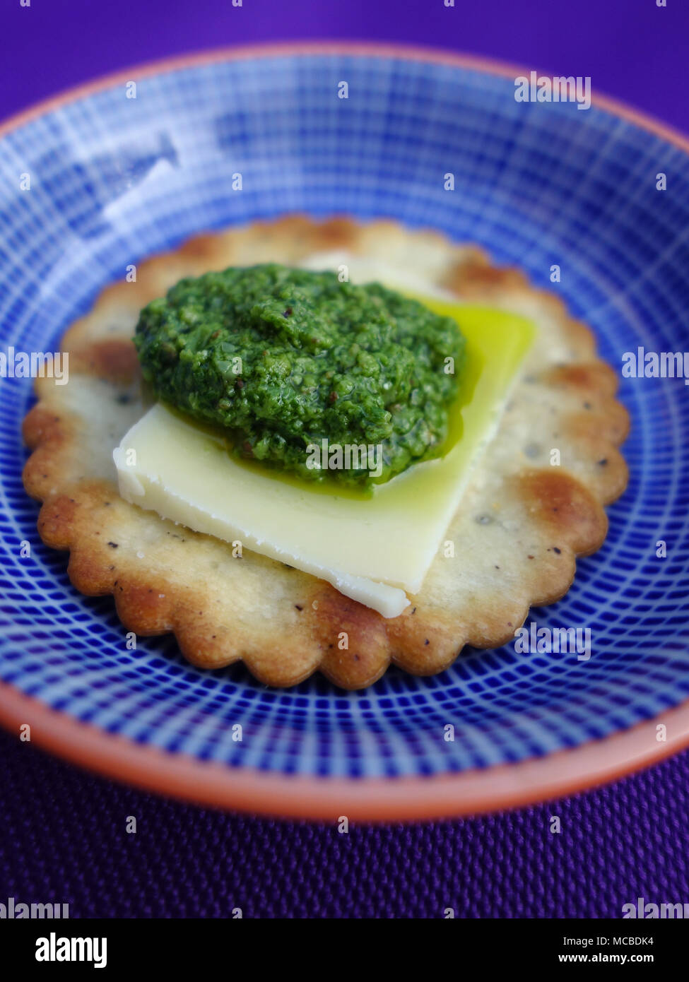 Bärlauch Pesto auf einem Cracker mit einem Stück Parmesan Stockfoto