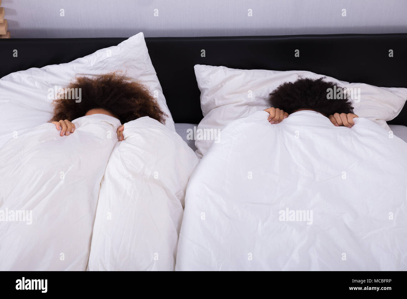 Ansicht von Paar, Ihr Gesicht mit weißen Blatt im Schlafzimmer Stockfoto