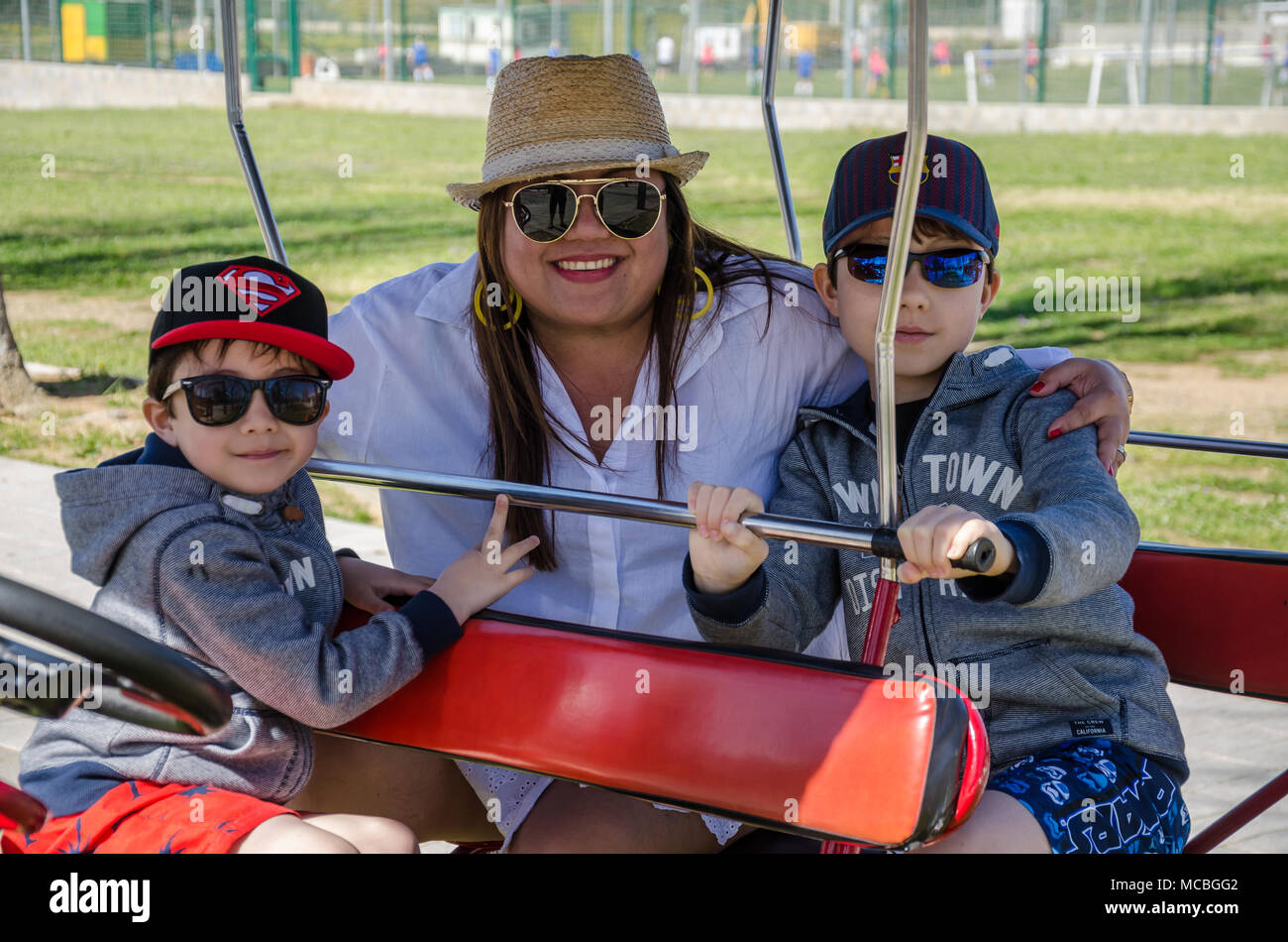 Eine Mutter und ihre junge Familie sitzen auf einem quadracycle und für ein Gruppenfoto posieren. Stockfoto