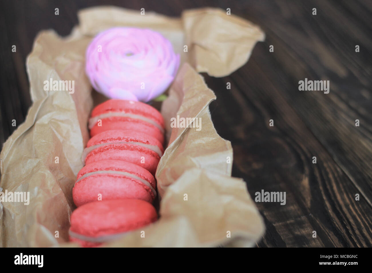 Bunte Makronen und Blumen auf dem Tisch. Süße macarons in Geschenkbox. Ansicht von oben Stockfoto