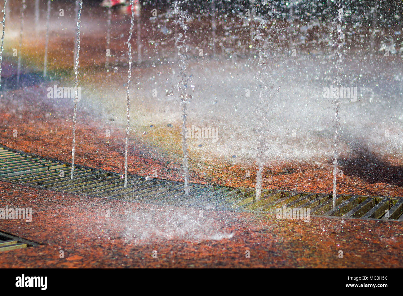 In der Nähe der schönen Stadt Brunnen. Spritzer nach oben Crystal thin Ströme von klaren kühlen Wasser, glänzenden Tröpfchen. Mehrfarbige verschwommen rainb Stockfoto
