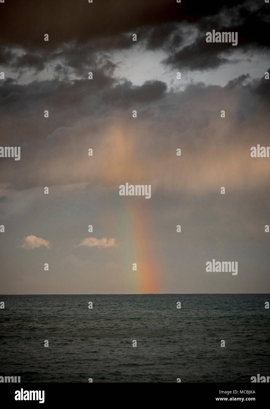 Rainbow mit dunklen Wolken über dem Meer, dramatische Atmosphäre Stockfoto