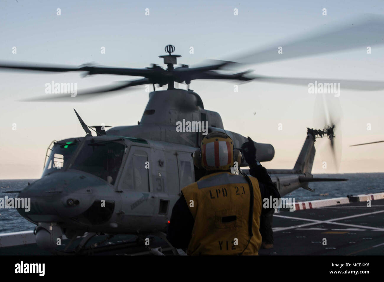 Pazifik (25. März 2018) Chef der Luftfahrt Bootsmann Mate (Kraftstoff) Horatio Johnson, von Miami, Fla., Signale an die Piloten einer UH-1Y Venom aus dem Marine Light Attack Helicopter Loslösung der Marine Medium Tiltrotor Squadron 166 verstärkt, die Aviation combat Element für die 13 Marine Expeditionary Unit (MEU), auf dem Flugdeck der San Antonio-Klasse amphibious Transport dock USS Anchorage LPD (23), während eine amphibische Squadron und MEU Integration (PMINT) Übung. PMINT ist ein Training Entwicklung zwischen Essex Amphibious Ready Gruppe und 13 MEU, Matrosen und Marines zu t Stockfoto