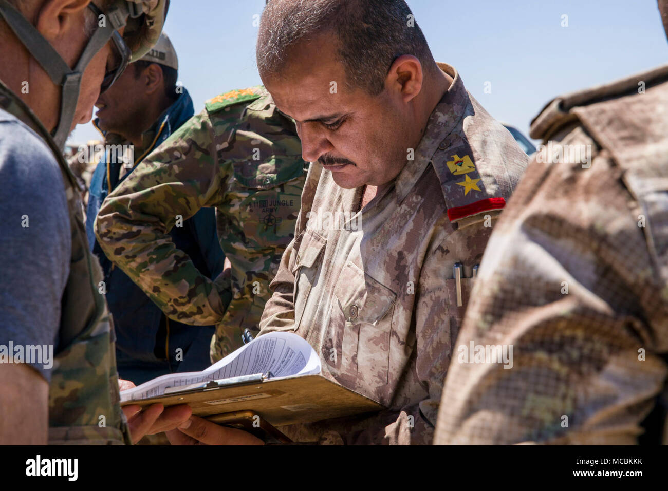 Ein Mitglied der irakischen Grenze wache Bewertungen Informationen über Ausrüstung aus der U.S. Army 249th Composite Supply Company übertragen werden, 82nd Airborne Division, im Camp Taji, Irak, 26. März 2018. Die USA bietet Ausbildung und Ausrüstung der irakischen Sicherheitskräfte durch die National Defense Authorization Act Geschäftsjahr 2015 geprüft; der Irak auszubilden und auszurüsten. Ausbildung und Ausrüstung zur Unterstützung der Combined Joint Task Force - inhärenten Lösen Mission zu besiegen und ISIS sicheren Zufluchtsort verweigern durch Erstellen und Aktivieren von irakischen Truppen zu verteidigen und ihr Land von sicheren Terroris Stockfoto