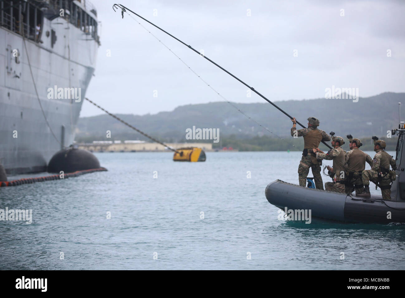 Ein US-Marine versucht, eine Kletterwand, Leiter Haken auf den u-boot Tender USS Frank Kabel (40) Während eines simulierten raid März 27, 2018, in Guam. Die US-Marines mit Force Reconnaissance Firma, 3 Reconnaissance Bataillon, 3rd Marine Division, III Marine Expeditionary Force mit British Royal Marines mit J Unternehmen zusammengetan, 42 Commando und US-Segler mit explosiven Verpackungsverordnung Entsorgung Mobile Unit 5 Verbindung zu leiten, kombinierte Ausbildung, um standard operating procedures in einem Besuch, Board, Durchsuchung und Beschlagnahme Umgebung, damit Sie bieten eine flexiblere und Mission gemeinsam zu entwickeln. Stockfoto