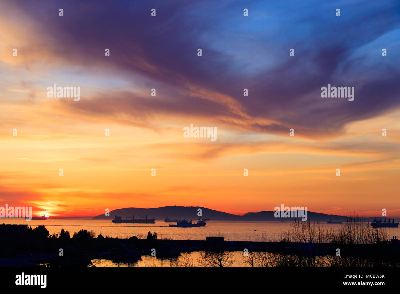 Fantastische Farben des Sonnenuntergangs im Hafen mit Reflexionen von ruhigen Meer - der Fokus ist auf die Horizonte Stockfoto