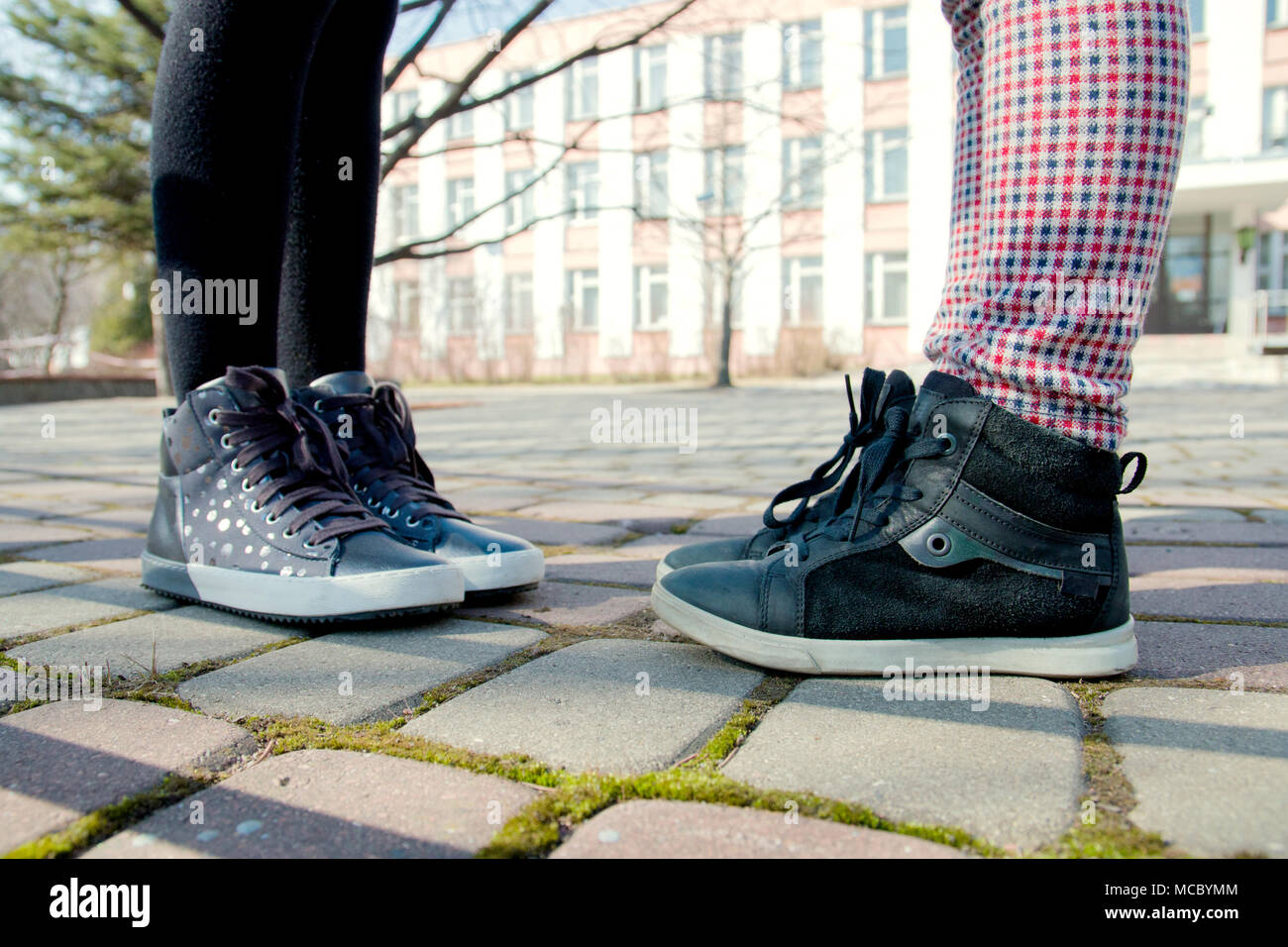 Die kinderfüße in grau Stiefel sind einander gegenüber auf dem Bürgersteig. Stockfoto