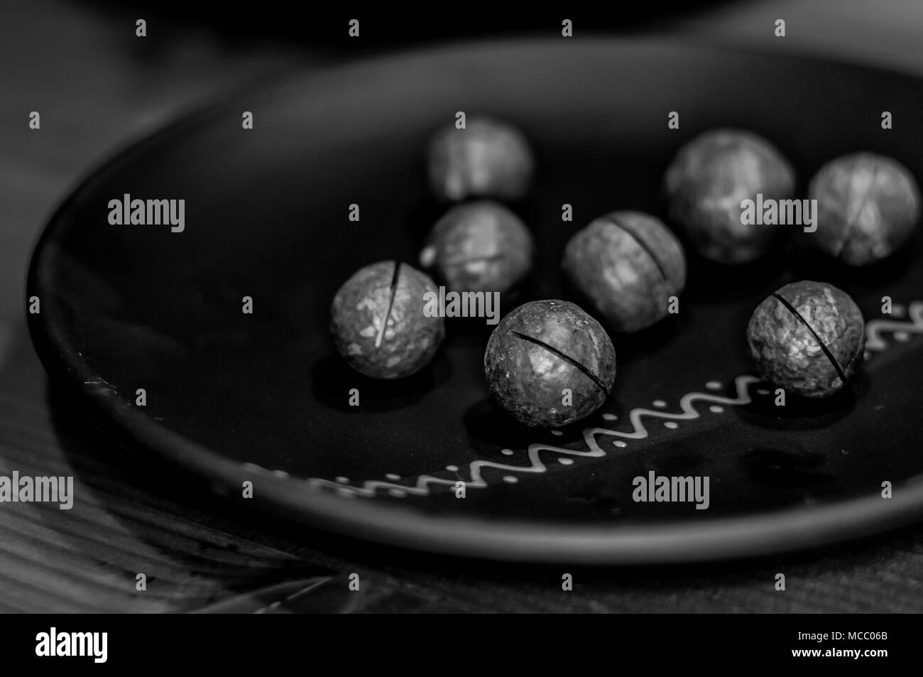 Macadamia, australische Mutter in einem keramischen Platte auf einem Holztisch, Nahaufnahme, getönt Stockfoto