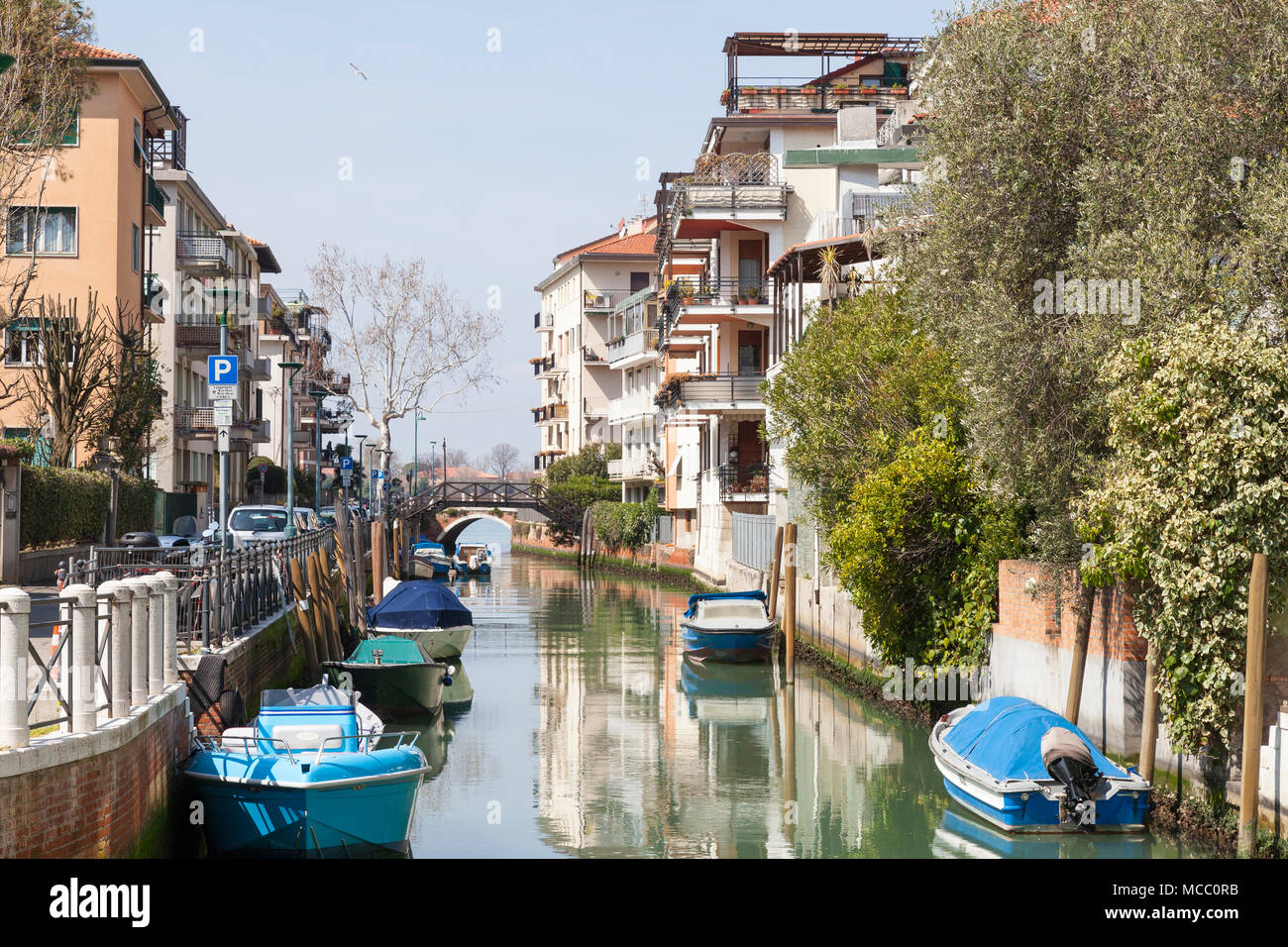 Ruhigen Kanal mit Reflexionen und angelegten Boote in Lido di Venezia (Venedig Lido, Lido Insel), Venedig, Venetien, Italien mit frühen Morgennebel auf der Stockfoto