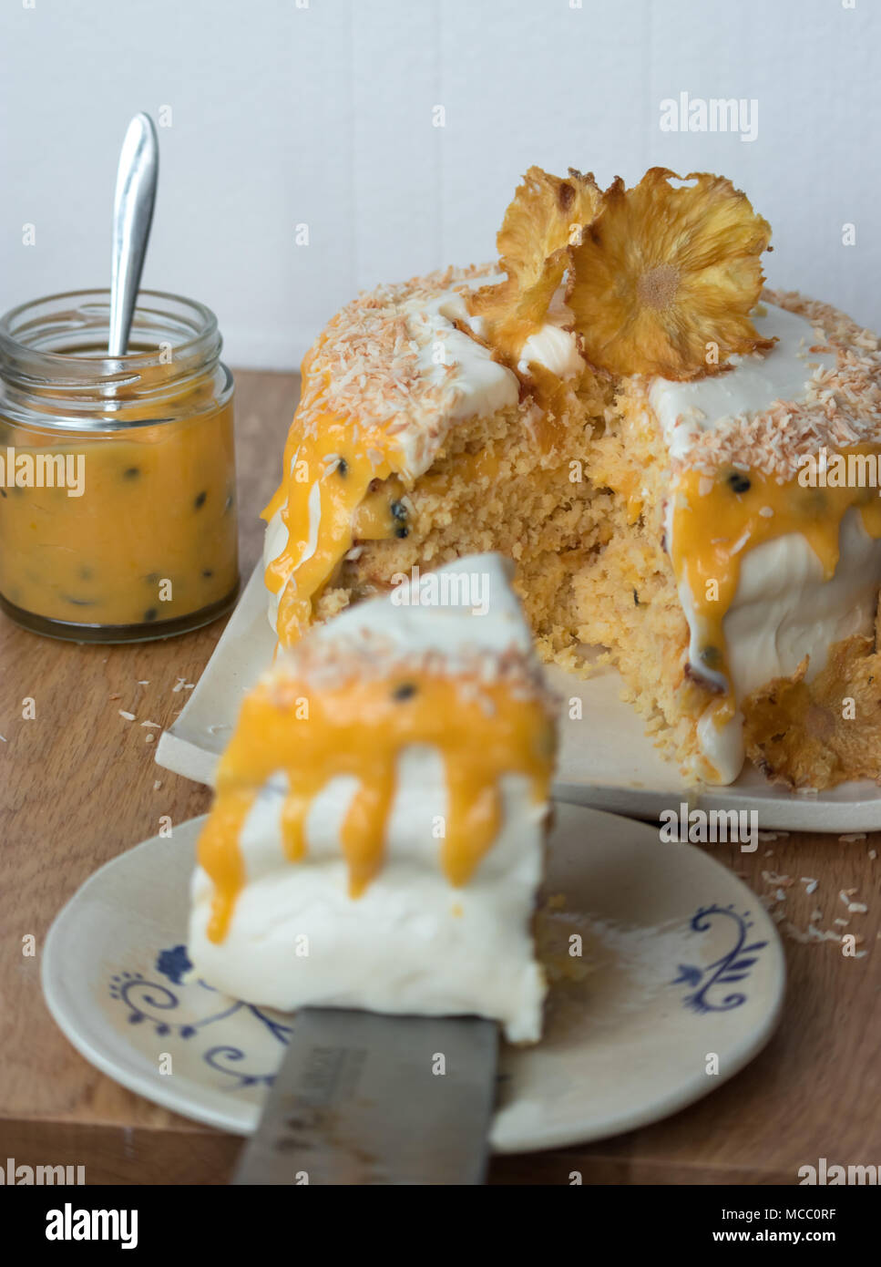 In Scheiben geschnittene Ananas und Kokosnuss Layer Cake, serviert mit Passionsfrucht Soße auf handgefertigte Keramik Platten. Stockfoto