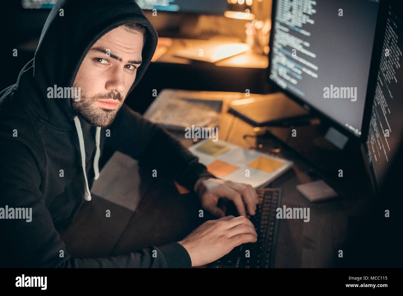 Gefährliche hooded Hacker an Kamera Codierung auf der Suche auf dem Computer organisieren cyber DDOS-Angriff, Programmierer in der Motorhaube hacking Spionage oder stehlen geheime informieren Stockfoto