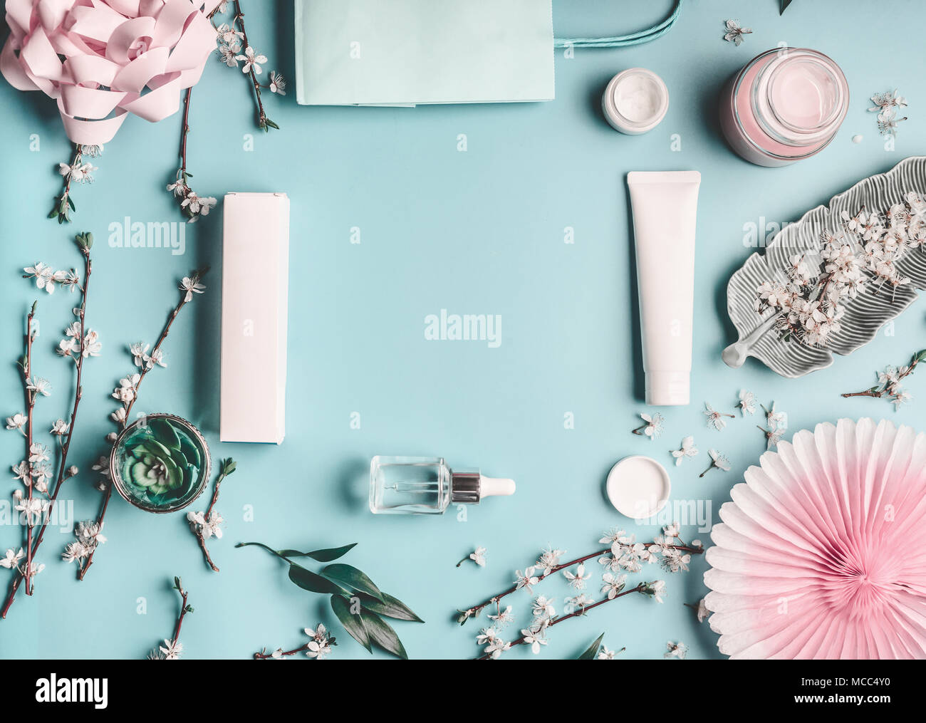 Schönheit Konzept mit Gesichts kosmetische Produkte, Shopping Bag und Zweige mit Cherry Blossom auf Pastell-blaue Desktop Hintergrund. Moderne Frühling Hautpflege tr Stockfoto