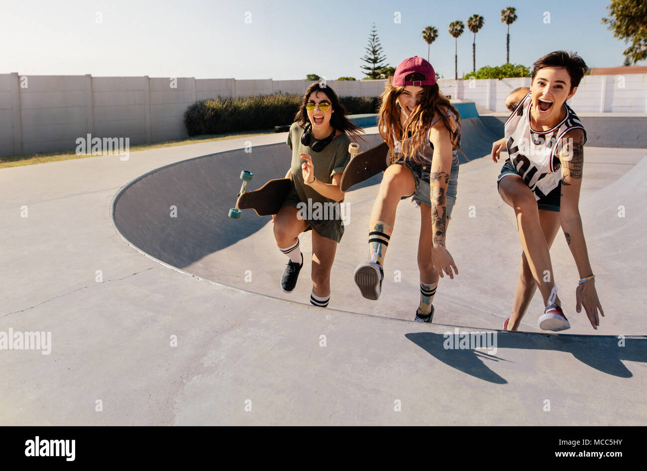 Lachende Frauen Klettern ein Skateboard Rampe. Gruppe von Mädchen, die eine großartige Zeit bei Skate Park. Stockfoto
