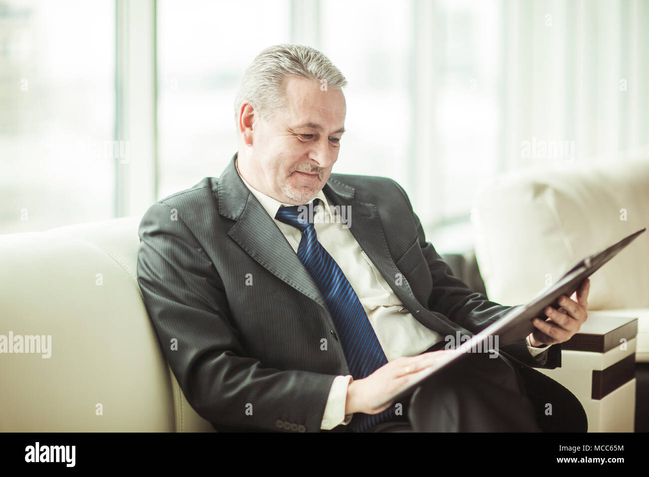 Erfolgreicher Geschäftsmann Studien Working Papers auf dem Sofa sitzen im eigenen Büro Stockfoto