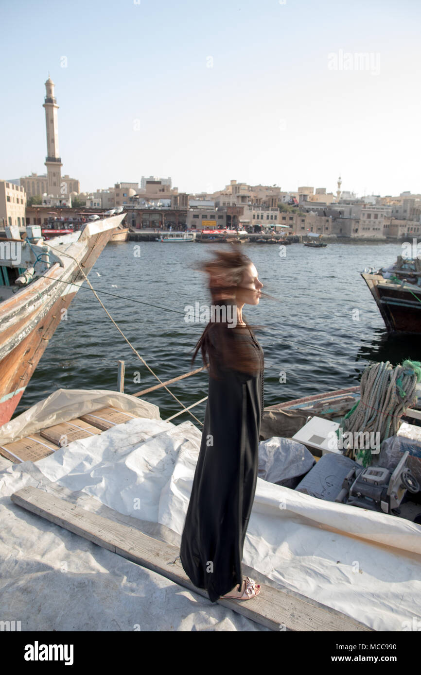 Frau gekleidet in abaya Wandern in der Nähe von alten Booten Stockfoto