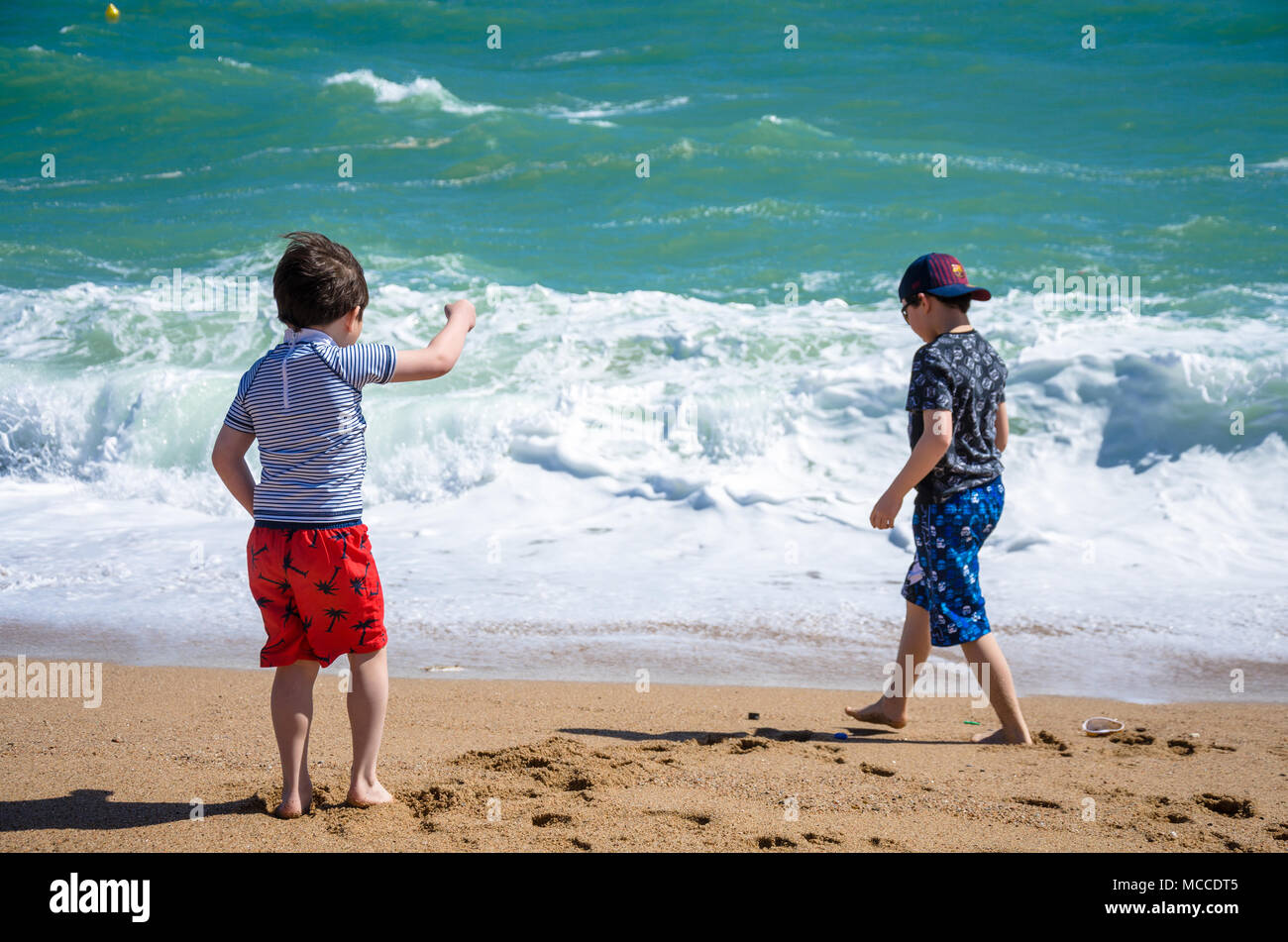 Zwei junge Brüder spielen gemeinsam an einem Sandstrand in der Nähe des Wasser. Stockfoto