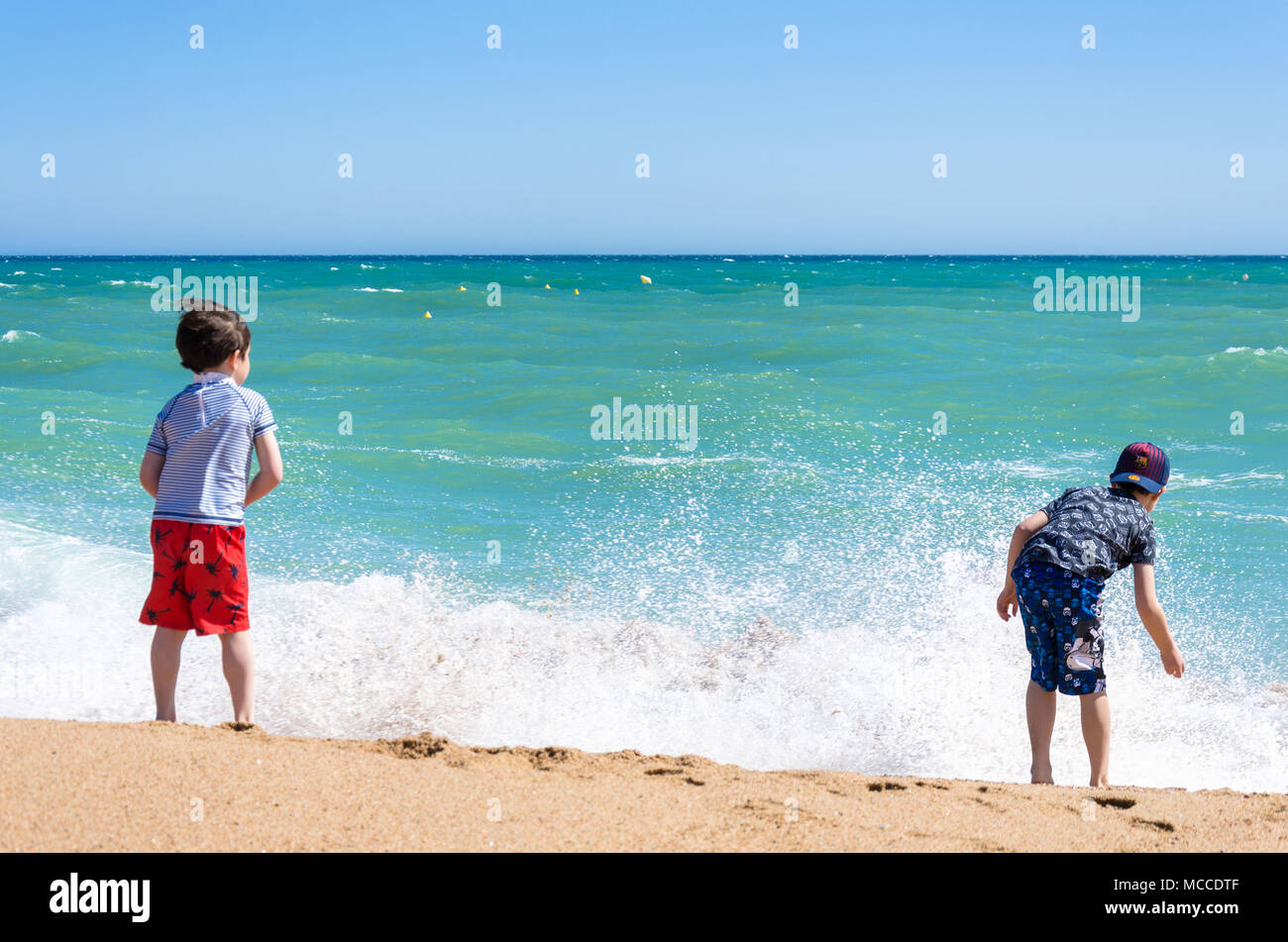 Zwei junge Brüder spielen gemeinsam an einem Sandstrand in der Nähe des Wasser. Stockfoto