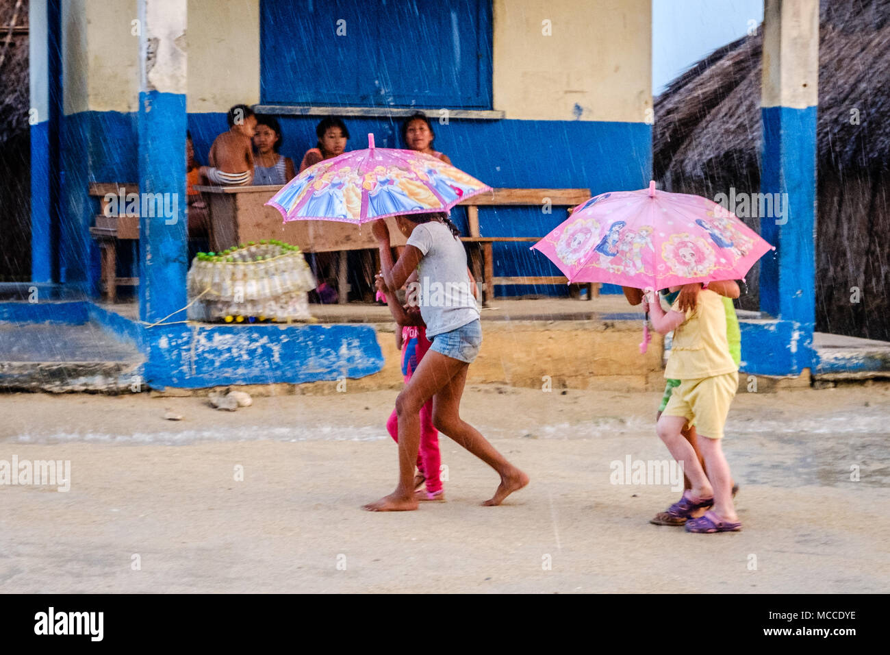 Guna Yala, Panama - März 2018: Die Gruppe der jungen Kinder mit Schirm im Regen auf der Straße in einem Kuna Dorf, San Blas Inseln Stockfoto