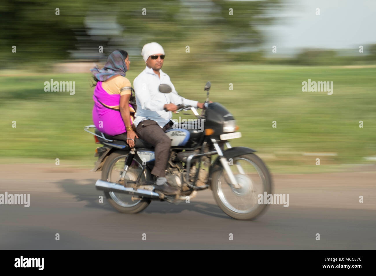 Eine Frau in einem Spree sitzen Seite Sattel als Passagier auf einer Beschleunigung Motorrad in Indien Stockfoto