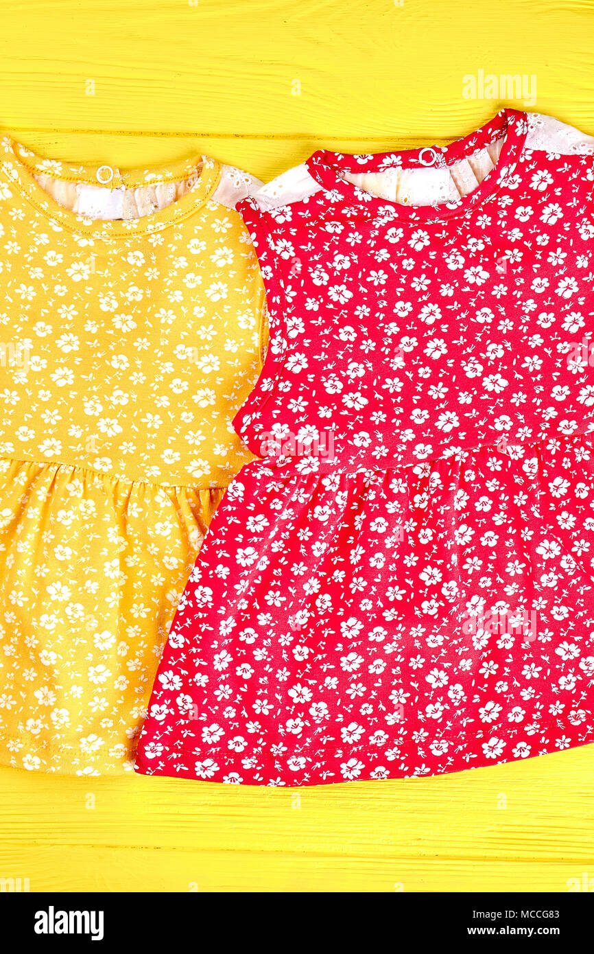 Satz von Babys Marke Kleider. Baby - Mädchen zwei farbige Kleider auf gelb Holz- Hintergrund, Ansicht von oben. Kleine Mädchen gedruckt Outfit. Stockfoto