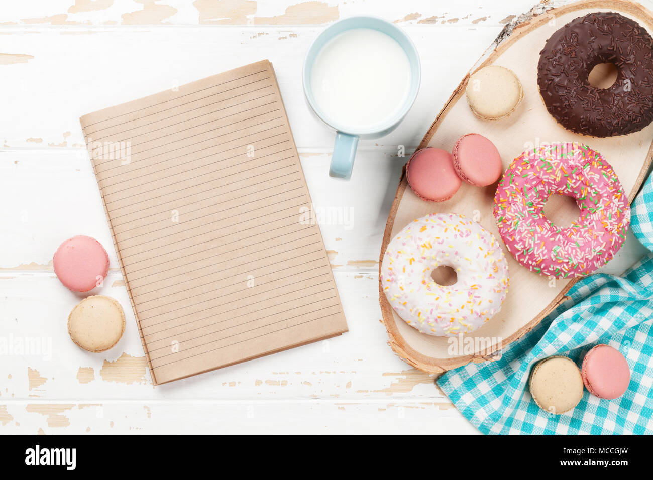 Milch, Makronen und Donuts auf Holztisch. Mit Notepad für Ihre Notizen Stockfoto