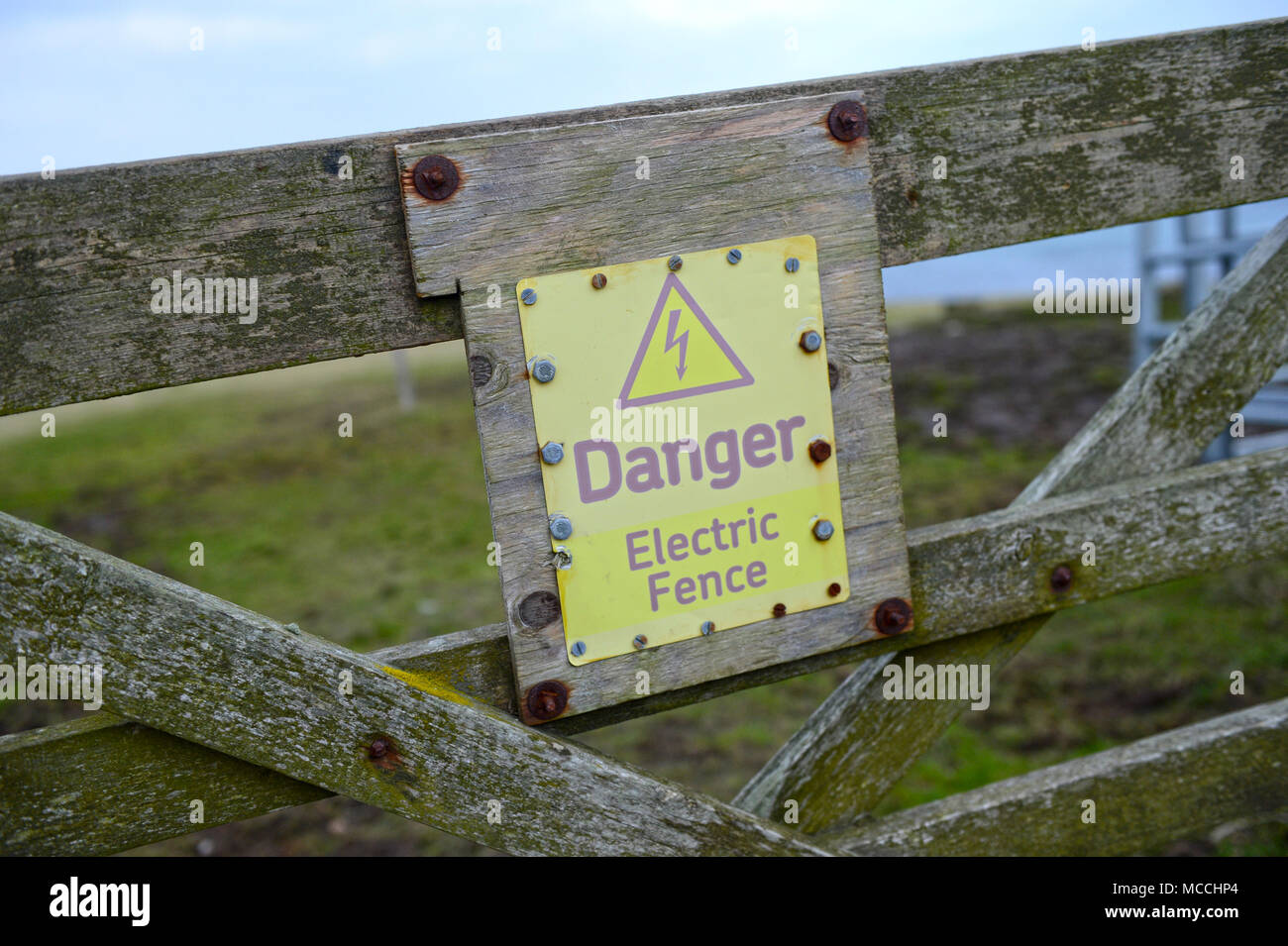 Verwitterte Gefahr durch elektrischen Zaun Zeichen Stockfoto