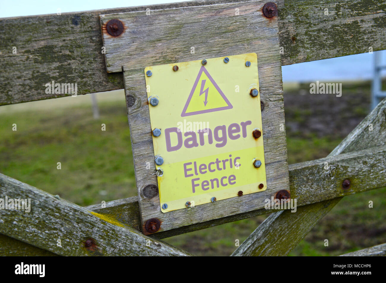 Verwitterte Gefahr durch elektrischen Zaun Zeichen Stockfoto
