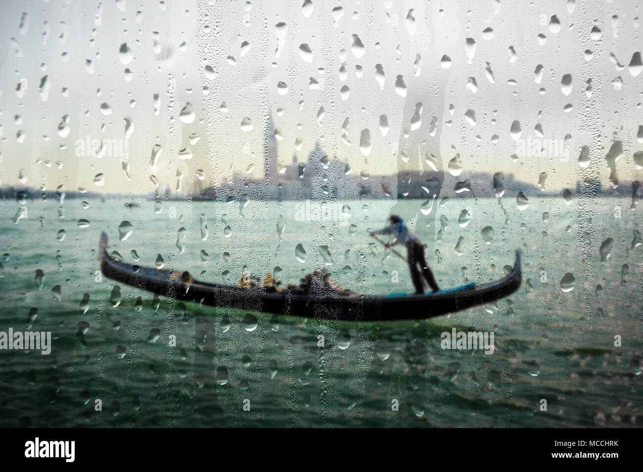 Ein unscharfer Gondoliere am Canal Grande hinter Glas voll Wasser tropfen, Venedig, Italien. Stockfoto