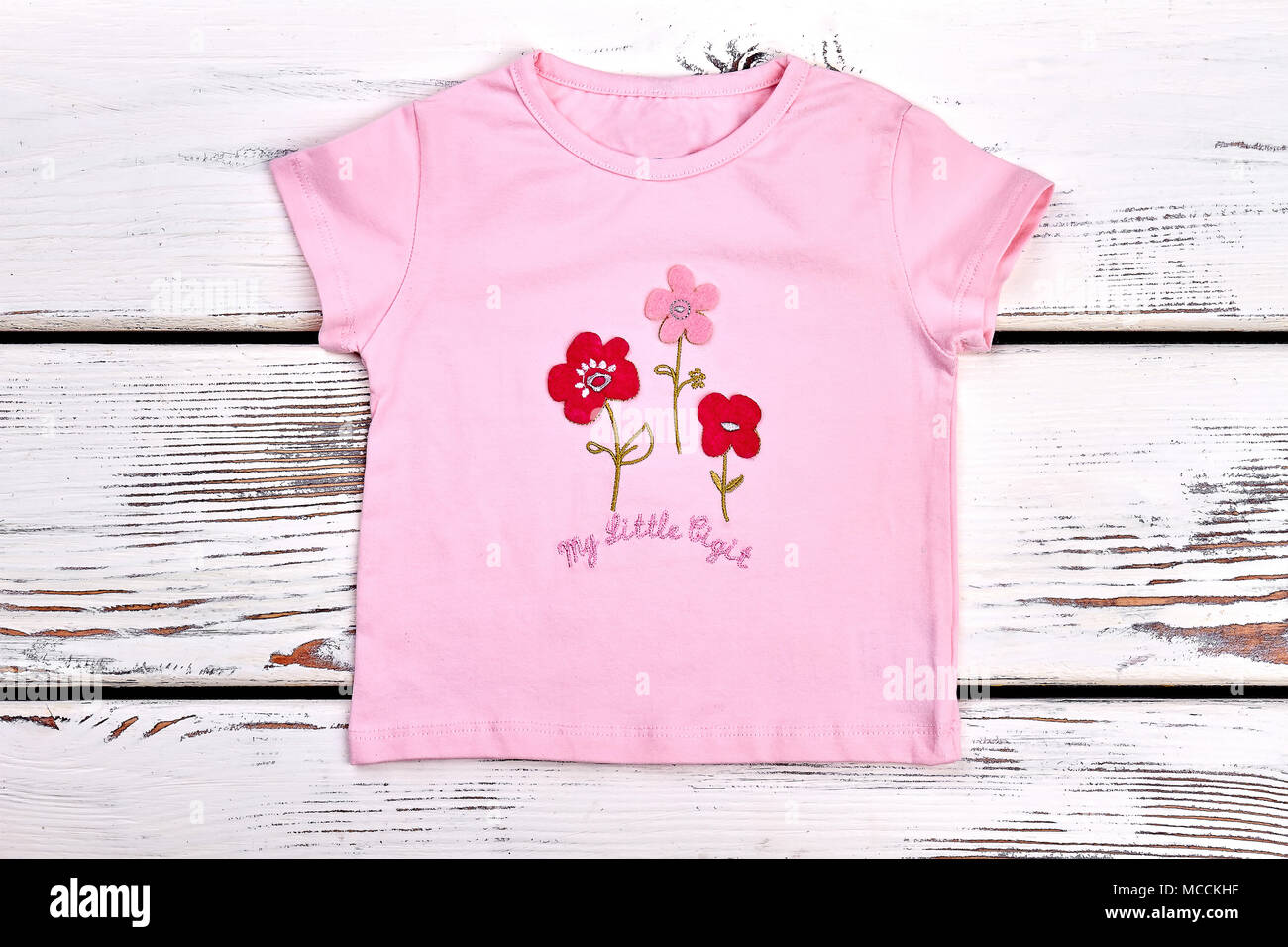 Toddler girl pink Cartoon-t-shirt. Baby - Mädchen casual rosa T-Shirt auf weißem Holz- Hintergrund. Stockfoto