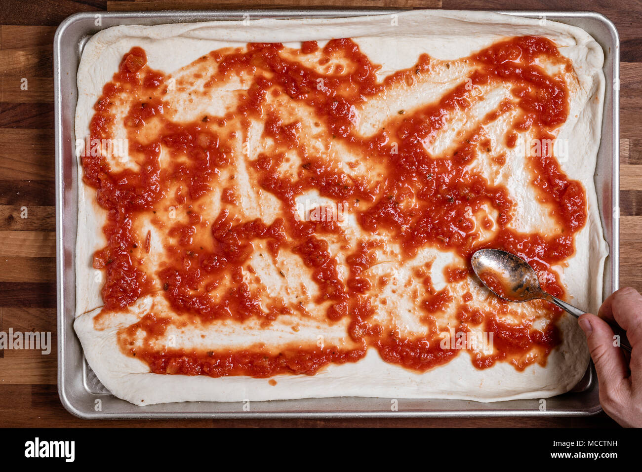 Mann Verbreitung Tomatensauce auf ausgerollten Teig für hausgemachte Pizza Stockfoto